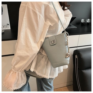 Detail view of light blue bucket bag with lychee texture and silver twist lock