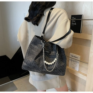 Detail der schwarzen Glitzer-Tote-Bag mit silbernen Ketten und eleganten weißen Perlen