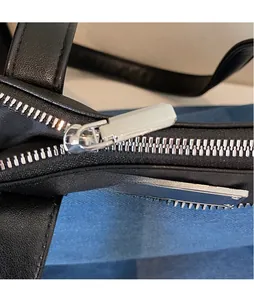 Detailed macro view of smooth silver metal zippers on high-quality black leather bag