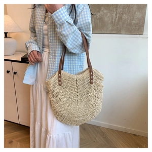 Detailed close-up of handmade straw tote bag with V-shaped weave and brown leather strap