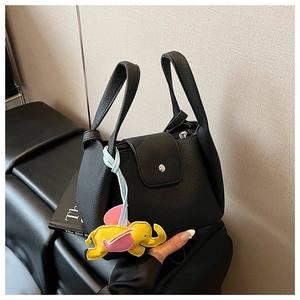 Detail of black lychee grain leather handbag with yellow elephant charm accessory