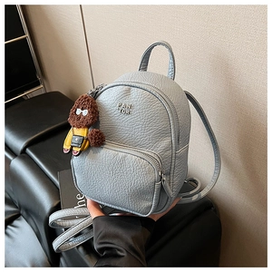 Détail d'un mini sac à dos gris en cuir avec un pendentif peluche ours brun