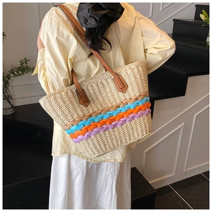 Close-up of woven straw tote bag with colorful stripes and brown leather strap detail