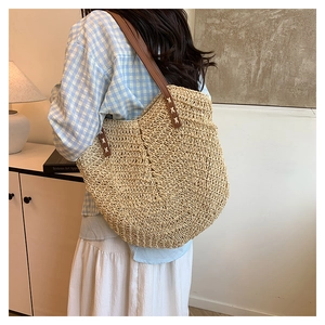 Detail of hand-woven straw tote with premium brown leather straps and V-shaped texture