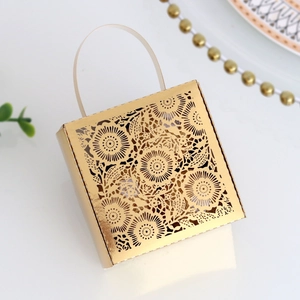 Close-up of golden laser-cut wedding favor box with floral pattern and frosted handle