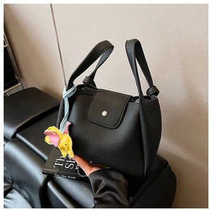 Detail of black lychee grain PU tote bag with magnetic flap and cute elephant charm