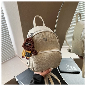 Détail du mini sac à dos en cuir crème avec zips argentés et pendentif chien en peluche