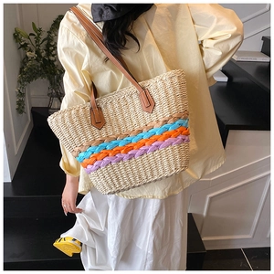 Dettaglio della trama della borsa in paglia con strisce arcobaleno e manici in pelle