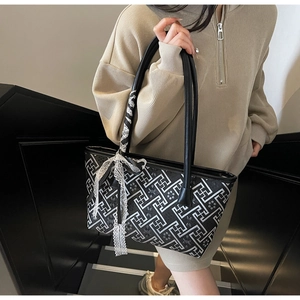 Detail of checkered tote bag featuring a decorative white lace bow and leather handles