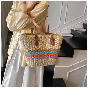 Detail of woven straw tote bag with colorful stripes and brown leather shoulder straps