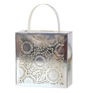 Detail of silver laser-cut floral pattern gift box with white handle for wedding favors