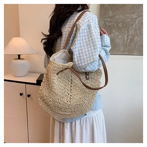 Detailed close-up of the woven texture and dark brown leather straps on the straw tote bag