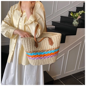 Detail of colorful woven stripes on a straw bucket bag with brown leather strap
