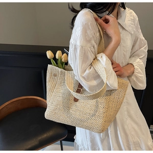 Détail du sac cabas en paille tissée avec sangle en cuir marron et intérieur spacieux
