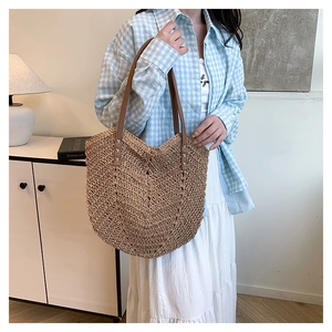 Detail of handcrafted straw tote bag with brown leather straps and rivet accents