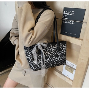 Detail of a chic tote bag with geometric floral patterns and a large lace bow decoration