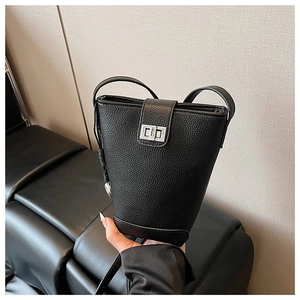 Detail of black pebbled leather bucket bag featuring a polished silver twist lock closure