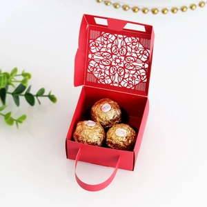 Close-up of red hollow-out lace wedding candy box with laser-cut patterns and top handle