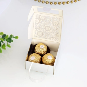 Detail of white laser-cut wedding favor box with floral patterns and handle