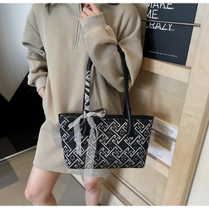 Detail of black and white geometric pattern tote bag with delicate side lace ribbon