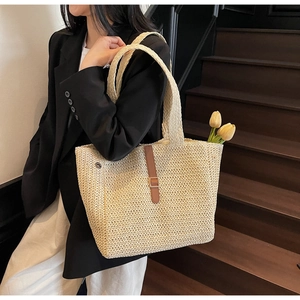 Détail d'un sac cabas en paille avec boucle en cuir et tulipe porté par un mannequin