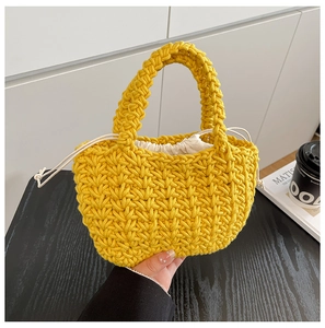 Detailed close-up of handmade bright yellow woven bucket bag with cream drawstring liner