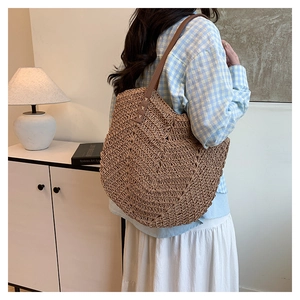 Detailed V-shaped weave texture on a handmade straw tote bag with brown leather strap
