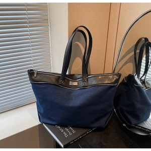 Detail of blue canvas tote bag with black leather handles and front decorative zipper