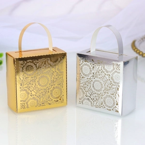 Detail of laser-cut gold and silver wedding favor boxes with floral hollow patterns