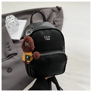 Détail d'un mini sac à dos noir en cuir grainé avec un porte-clé de chiot mignon
