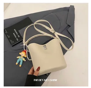 Detail of off-white bucket bag with lychee leather texture and silver metal twist lock