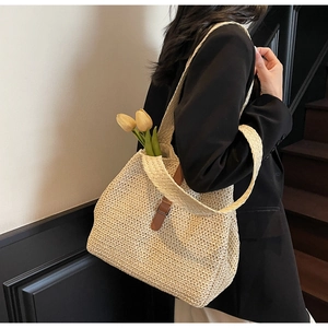 Détail du sac cabas en paille naturelle avec fermoir en cuir marron et texture tissée