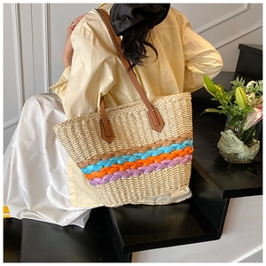 Detail of colorful woven stripes and brown leather strap on a straw tote bag