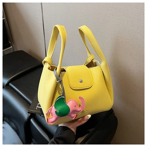 Detail of yellow lychee grain leather handbag with pink elephant charm and flap