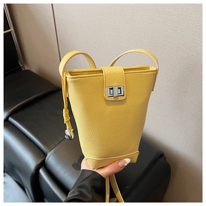 Detail of yellow pebble leather bucket bag featuring a silver twist lock and slim strap