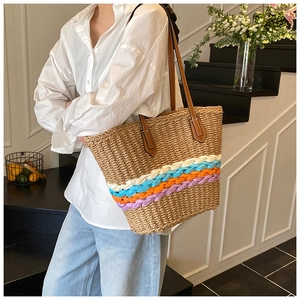 Dettaglio delle strisce colorate su una borsa in paglia con manici in pelle marrone