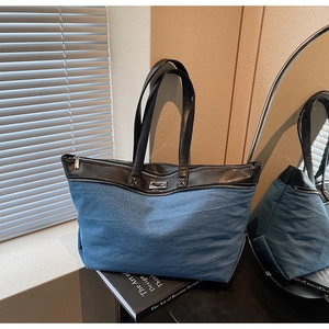 Detail of denim and leather tote bag with metallic logo on Art of Design book