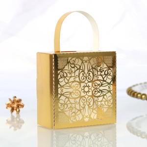 Close-up of golden hollow lace candy box featuring laser-cut floral patterns and handles