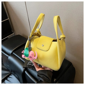 Detail of yellow lychee grain leather tote bag with a cute pink elephant charm