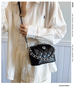 Detail of black quilted leather crossbody bag with silver chain and turn-lock