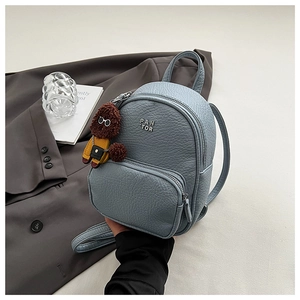 Détail du mini sac à dos en cuir bleu clair avec logo argenté et pendentif ours en peluche