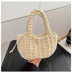 Detail of woven cream handbag featuring chunky knit texture and drawstring closure