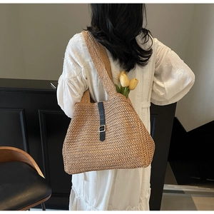 Detail of woven straw tote bag with black leather strap and golden buckle for summer