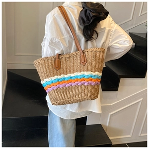 Dettaglio della borsa tote intrecciata a righe colorate con manici in pelle marrone