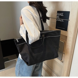 Detailed side view of a large black denim tote bag featuring a silver metal zipper closure