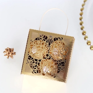 Detailed close-up of hollow lace-cut golden gift box with fine chocolates inside