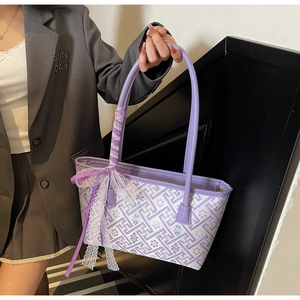 Detail of purple woven tote bag featuring floral geometric patterns and lace bow accessory