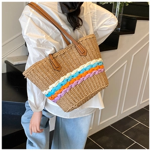 Detail of colorful striped straw bucket bag with dark brown leather handle and rivets