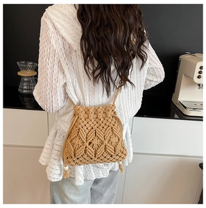 Detail of macrame woven crossbody bucket bag with drawstring and white bead accents