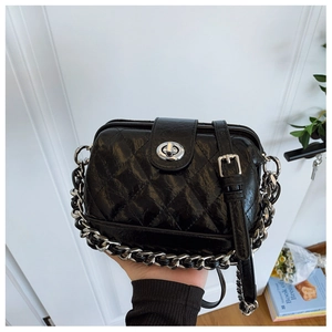 Detailed macro view of black quilted leather bag with silver metal chain and twist lock
